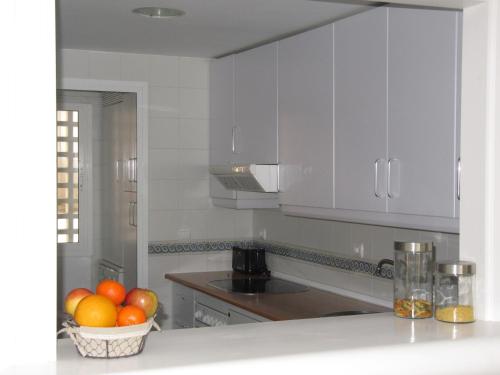 a kitchen with white cabinets and a basket of oranges at Life Apartments Costa Ballena in Costa Ballena