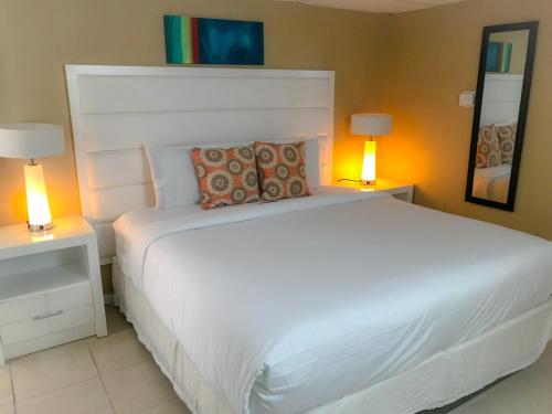 a bedroom with a large white bed with two lamps at Haven Hotel - Fort Lauderdale Airport & Cruise Port in Fort Lauderdale