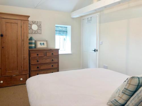 a bedroom with a white bed and a wooden dresser at Bakers Court in East Rudham