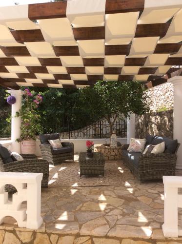 a patio with couches and chairs under a wooden ceiling at Villa Ampelaki 2 in Paleokastritsa