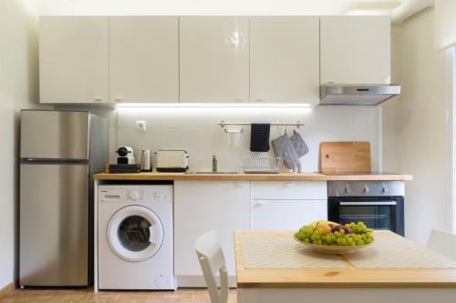 een keuken met witte kasten en een tafel met een fruitschaal bij Heraklion Urban Apartments in Heraklion