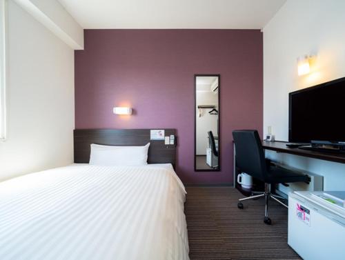 a bedroom with a bed and a desk and a computer at Super Hotel Hachinohe Tennen Onsen in Hachinohe