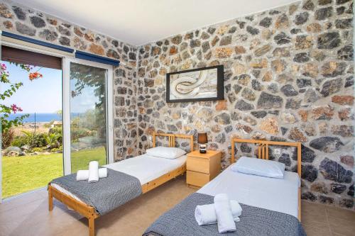 2 camas en una habitación con una pared de piedra en Villa Helios, en Kalathos