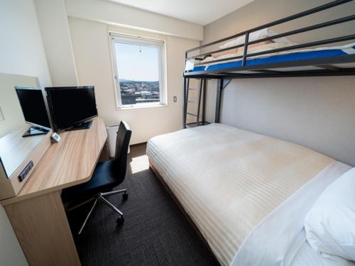 a bedroom with a desk with a computer and a bed at Super Hotel Hachinohe Nagayokocho in Hachinohe