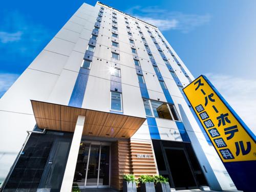 Super Hotel Hachinohe Nagayokocho في هاتشينوه: مبنى طويل مع علامة أمامه