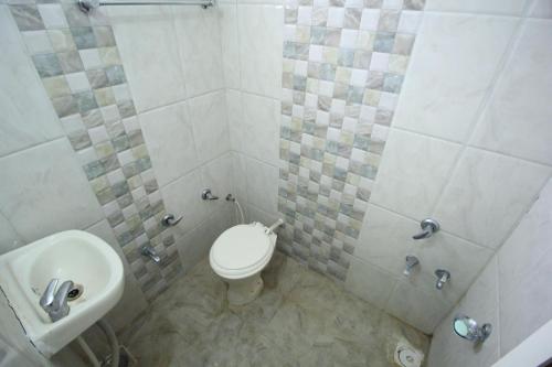 a bathroom with a toilet and a sink at Hotel Hillton in Gandhinagar