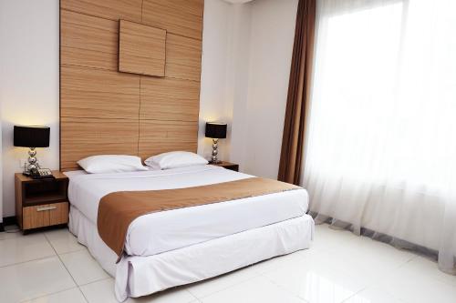 a bedroom with a large bed with a wooden headboard at Royal Hotel Bogor in Bogor