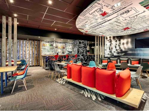 un restaurant avec des chaises et des tables rouges dans une salle dans l'établissement ibis Site du Futuroscope, à Chasseneuil-du-Poitou