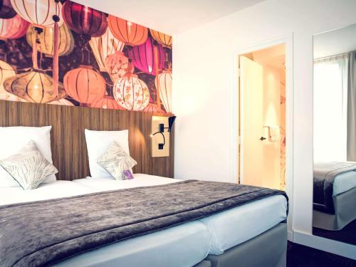 a bedroom with a large bed with a colorful wall at Mercure Lyon Centre Plaza République in Lyon