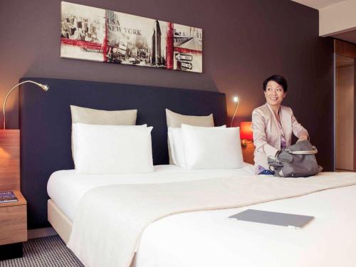 a woman sitting on a bed in a hotel room at Mercure Hotel Den Haag Central in The Hague