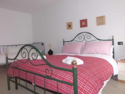 a bedroom with a bed with a red blanket and pink pillows at Casa Fattorini in Baceno