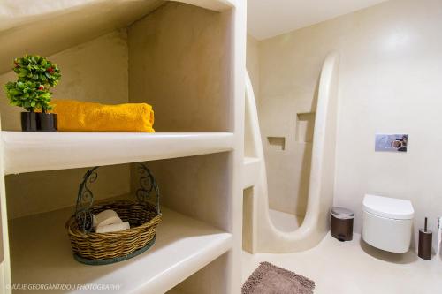 a bathroom with a basket of towels and a toilet at Aerides Villas in Naxos Chora