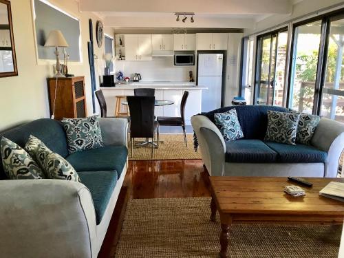 a living room with two couches and a table at Lakeview Cottage in Forster