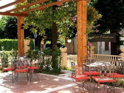 a group of tables and chairs under a pergola at Petit Chateau in Montecatini Terme