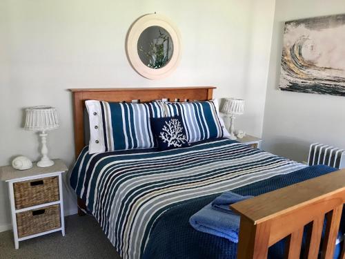 a bedroom with a bed with blue and white sheets at Lakeview Cottage in Forster