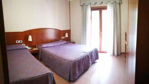 a hotel room with two beds and a window at Hotel Willy in Gemona del Friuli