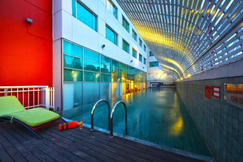 una piscina en un edificio con un banco al lado en HARRIS Hotel & Convention Festival Citylink Bandung en Bandung