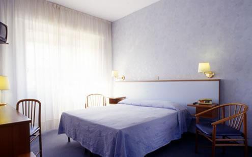 a bedroom with a bed and two chairs and a window at Hotel Riviera in Celle Ligure