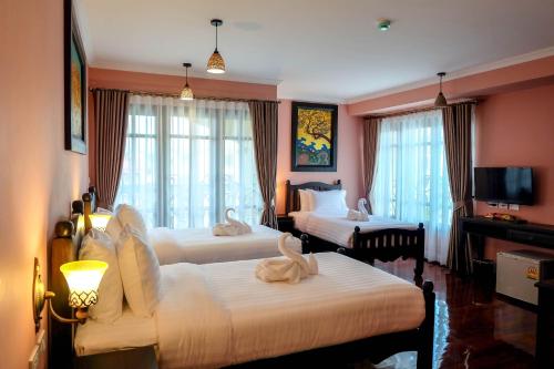 a hotel room with two beds and a television at Siri Heritage Bangkok Hotel in Bangkok