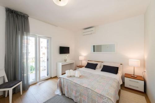 a white bedroom with a bed and a large window at Apartments Medora in Rovinj