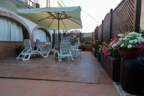a patio with chairs and an umbrella and flowers at La Casa di Gigliola in Monticiano