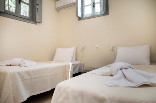 a room with two beds with white sheets and windows at villa aneme Spetses in Spetses