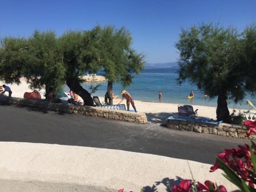 a group of people sitting on a beach near the water at Penthouse Apartments Ana in Sutivan