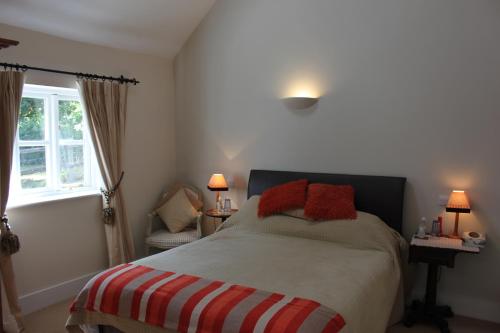 een slaapkamer met een bed met rode kussens erop bij High Street Farm Barn in Newbury