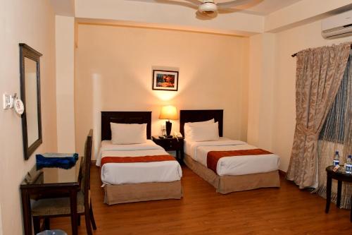 a hotel room with two beds and two lamps at Royalton Hotel Rawalpindi in Rawalpindi
