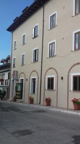 duży biały budynek z oknami wychodzącymi na ulicę w obiekcie Albergo Il Cacciatore w mieście Ovindoli