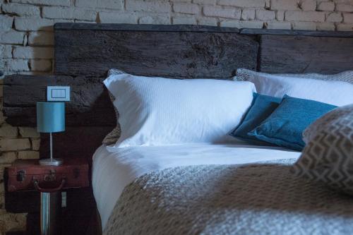 a bed with white sheets and pillows next to a brick wall at La Canonica - charming self-catering apartments in Nizza Monferrato in Nizza Monferrato