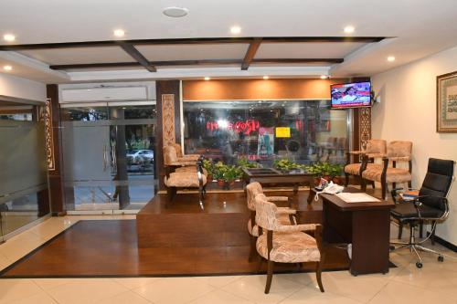 a lobby with chairs and a table and a tv at Royalton Hotel Rawalpindi in Rawalpindi
