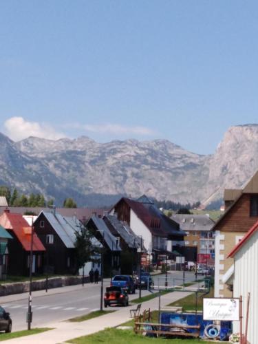 a town with mountains in the background with a street at Apartments Durmitor in Žabljak