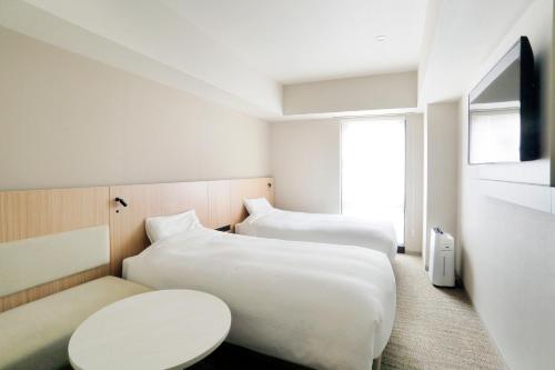 a hotel room with two beds and a table at JR Inn Sapporo-eki Minami-guchi in Sapporo