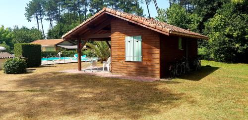 une petite maison en bois avec une fenêtre et une piscine dans l'établissement Chalet Saint Julien en Born, à Saint-Julien-en-Born