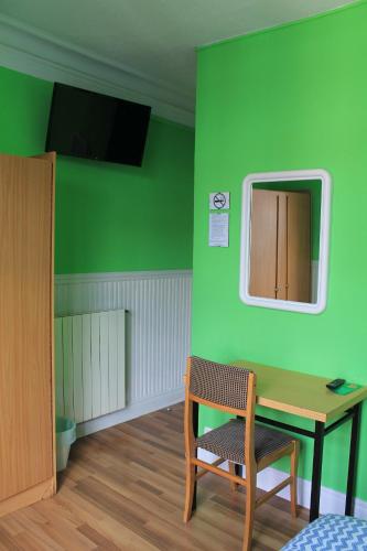 Habitación verde con mesa y silla en Pensión Manoli en Bilbao