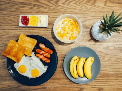 a wooden table with plates of breakfast food with eggs bananas and carrots at Varmtel in Bangkok