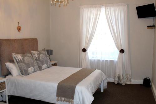 a bedroom with a bed and a window at Boer & Brit in Graaff-Reinet
