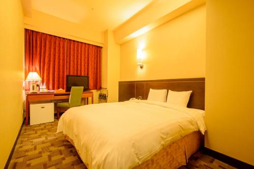 a hotel room with a bed and a desk with a computer at LA HOTEL- Liuhe Fusing in Kaohsiung