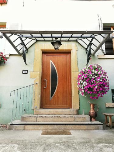 une porte en bois sur un bâtiment avec un pot de fleurs dans l'établissement Aux 6 hirondelles, à Ammerschwihr
