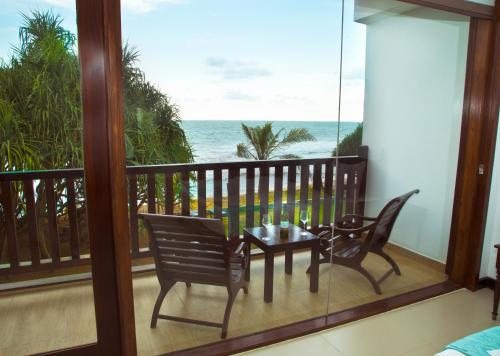 a balcony with a table and chairs and the ocean at The Pleasure Kosgoda in Bentota