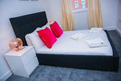 a bedroom with a bed with two red pillows on it at Superior 2 bedroom Apartments in Woolwich
