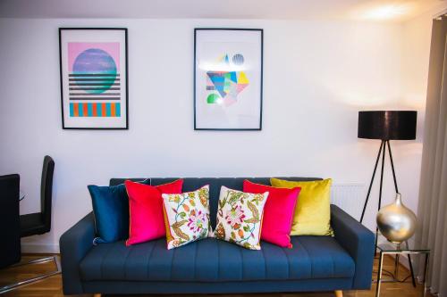 a blue couch with colorful pillows in a living room at Superior 2 bedroom Apartments in Woolwich