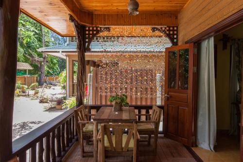 un porche de madera con mesa y sillas. en Anse Severe Beach Villas, en La Digue