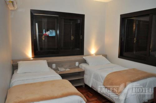 two beds in a room with a tv and two windows at Hotel Lages in Tabapira