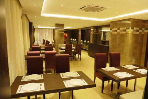 a dining room with tables and chairs and a kitchen at Avenue Hotel in Chennai