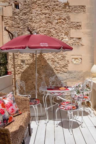 a table and chairs with a red umbrella on a patio at à Marchisa -Noto- in Noto