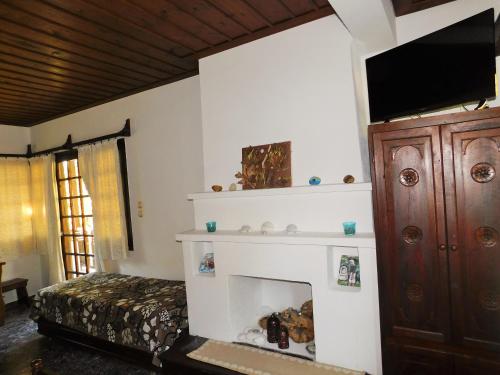 sypialnia z kominkiem i telewizorem na ścianie w obiekcie Guesthouse To kalivi w mieście Chorefto