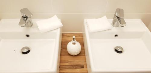 a bathroom with two white sinks and a vase at Le Particulier - Appart Hotel in La Réole
