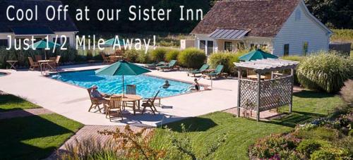 a swimming pool with tables and umbrellas in a yard at Parsonage Inn Bed and Breakfast in Saint Michaels